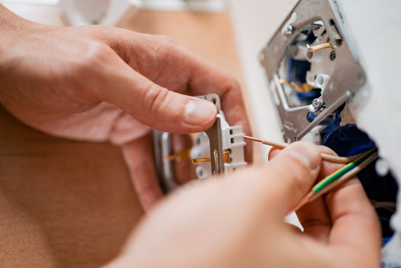 Hands wiring an electrical outlet in a wall box