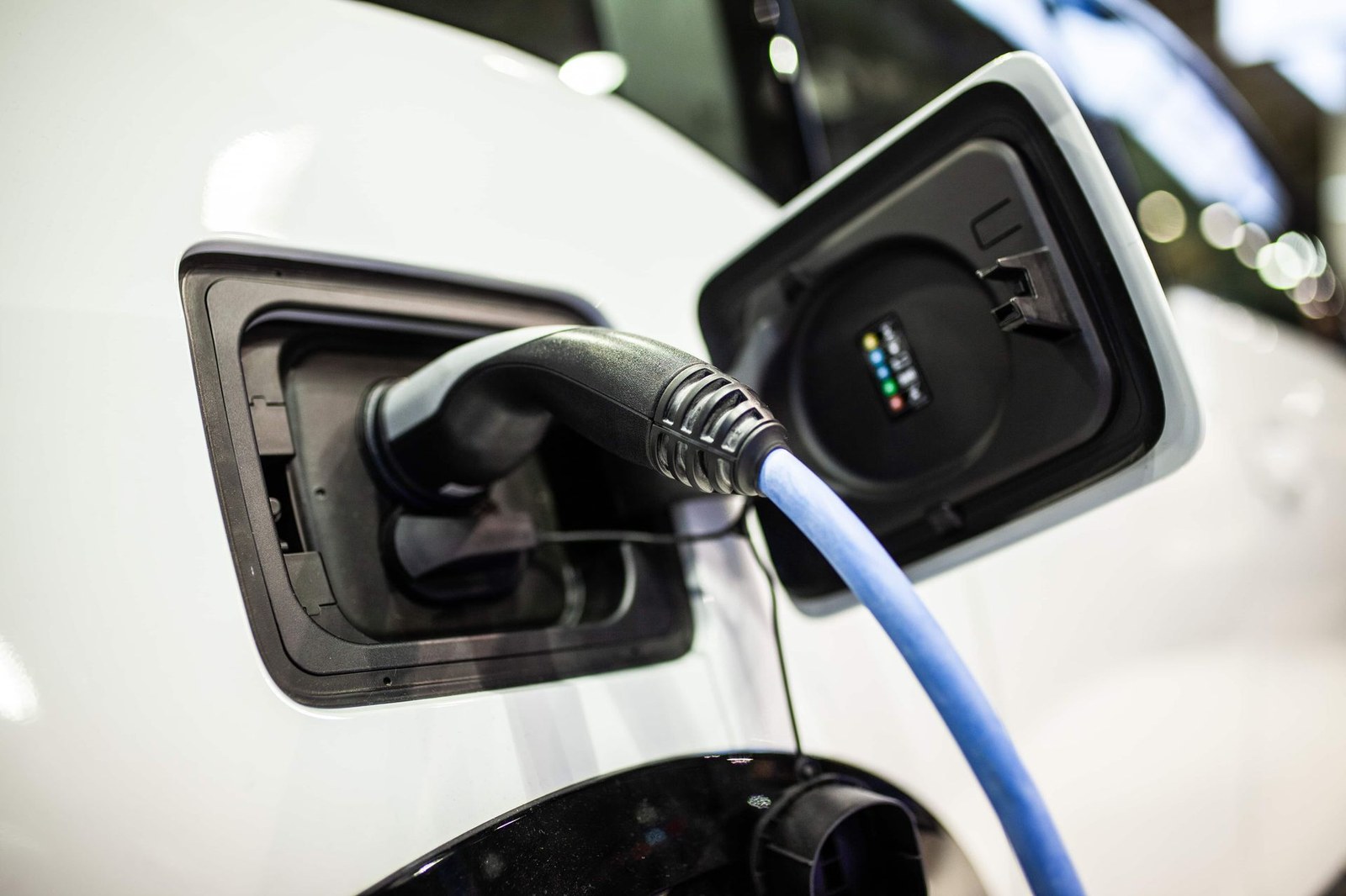 Electric car charging port with a blue cable plugged into a white vehicle