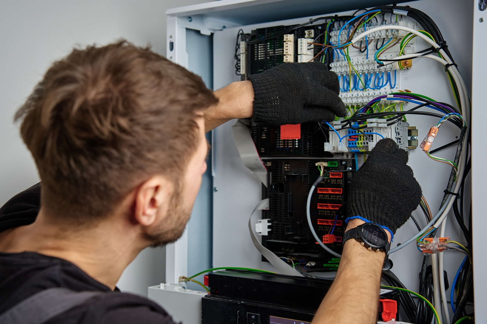 Electrician working on wiring inside an electrical control panel